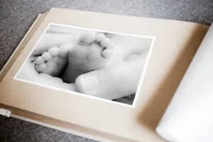 Mano sosteniendo huellas de pies de bebé en álbum de fotos, recuerdo especial de maternidad.