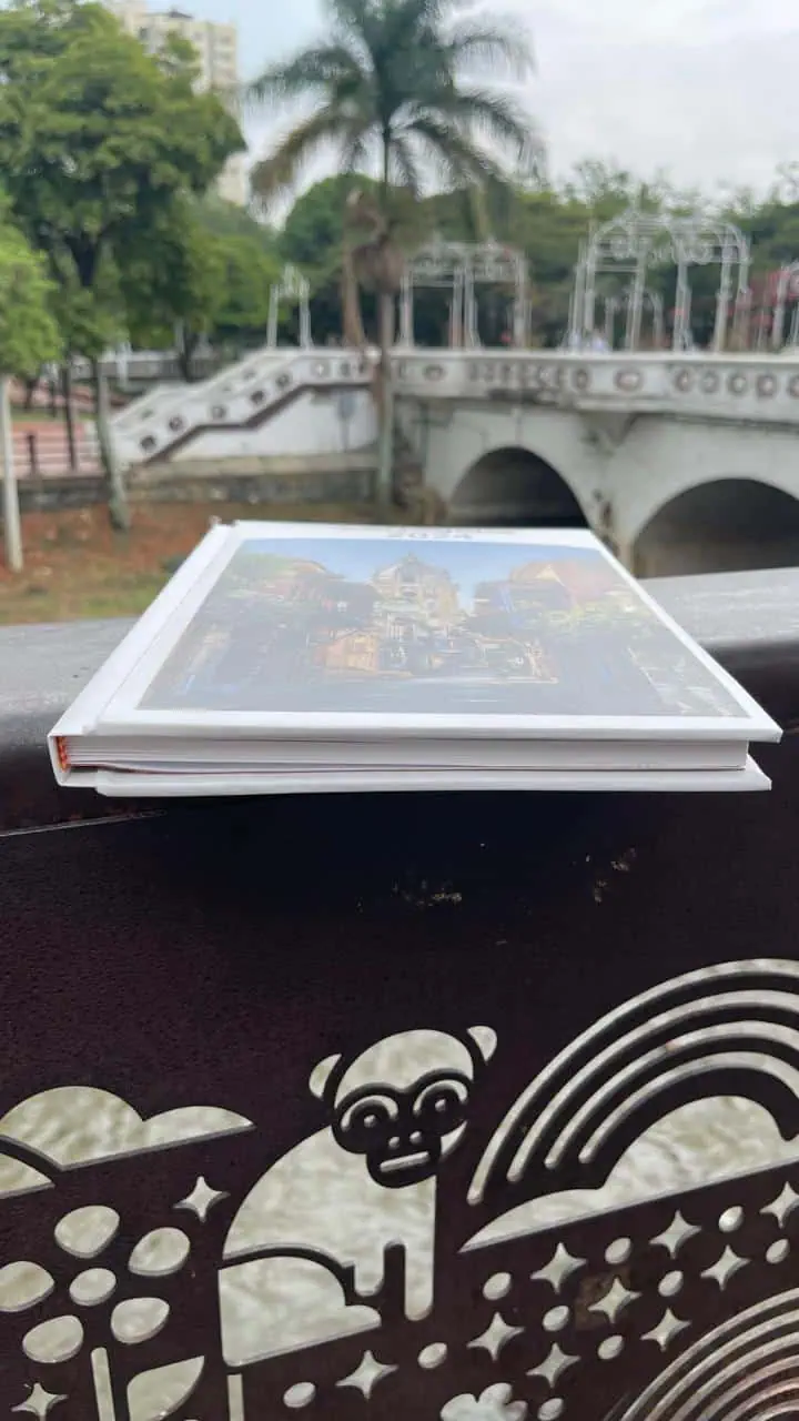 Libro turístico en parque con puente y palmera en fondo, lugar emblemático de Colombia.