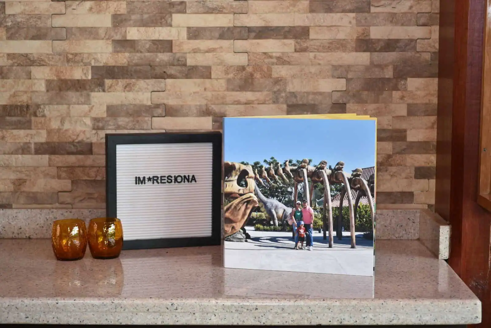 Letrero con frase "IM PRESIÓN" y foto de familia en parque de esculturas, decorativo y promocional para marca Impress.