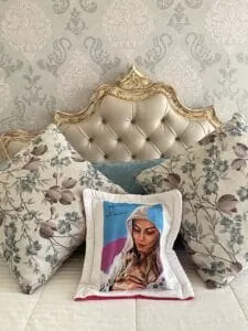Relajante cama con almohadas decorativas y cabecera vintage, decorada con papel pintado elegante.